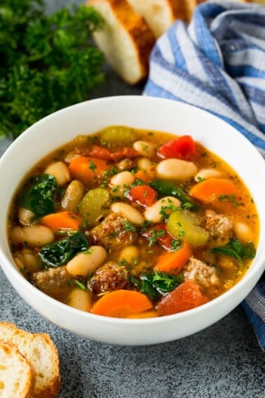 A bowl of white bean soup with Italian sausage, tomatoes and spinach.