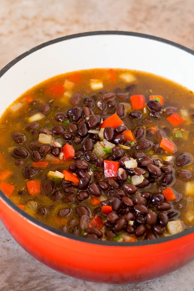 A pot of black beans, broth and vegetables.