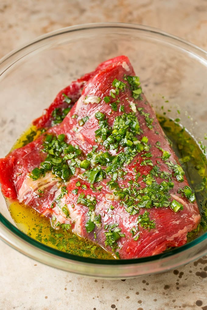 A flank steak in a bowl of carne asada marinade.