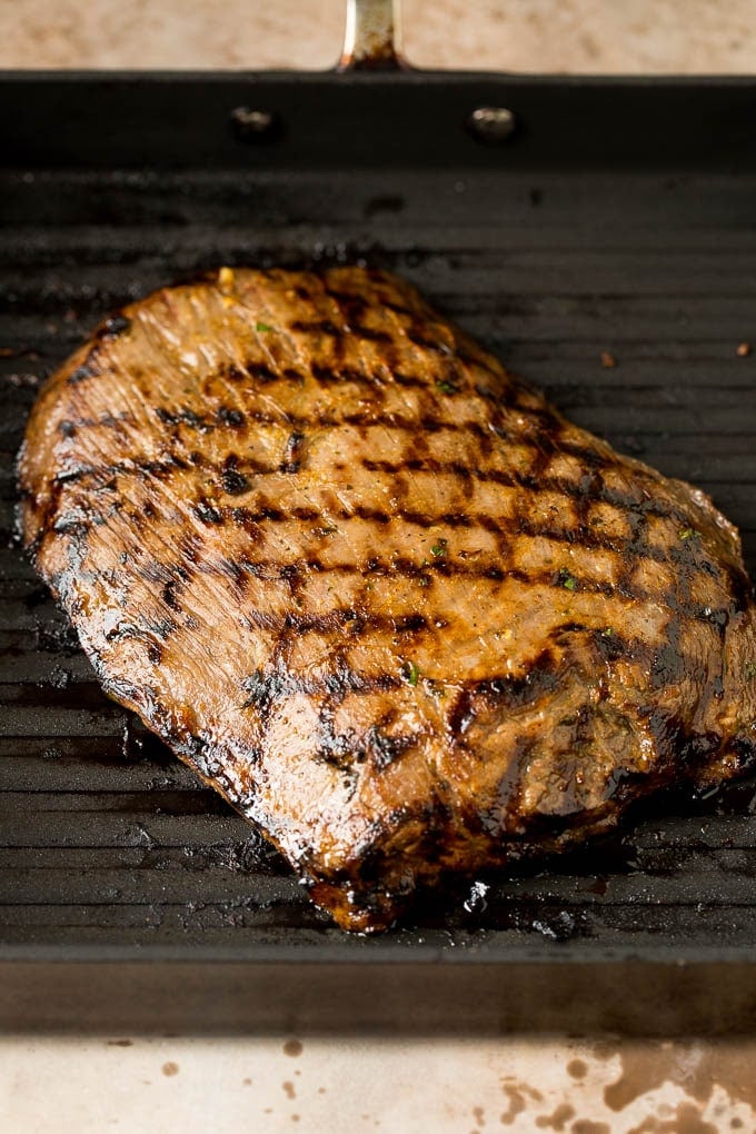 Grilled flank steak on a pan.