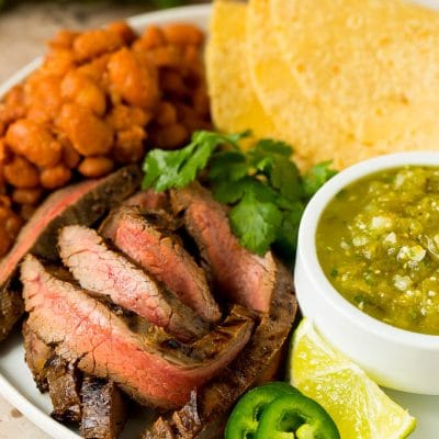 Grilled steak in carne asada marinade served with salsa, tortillas and beans.