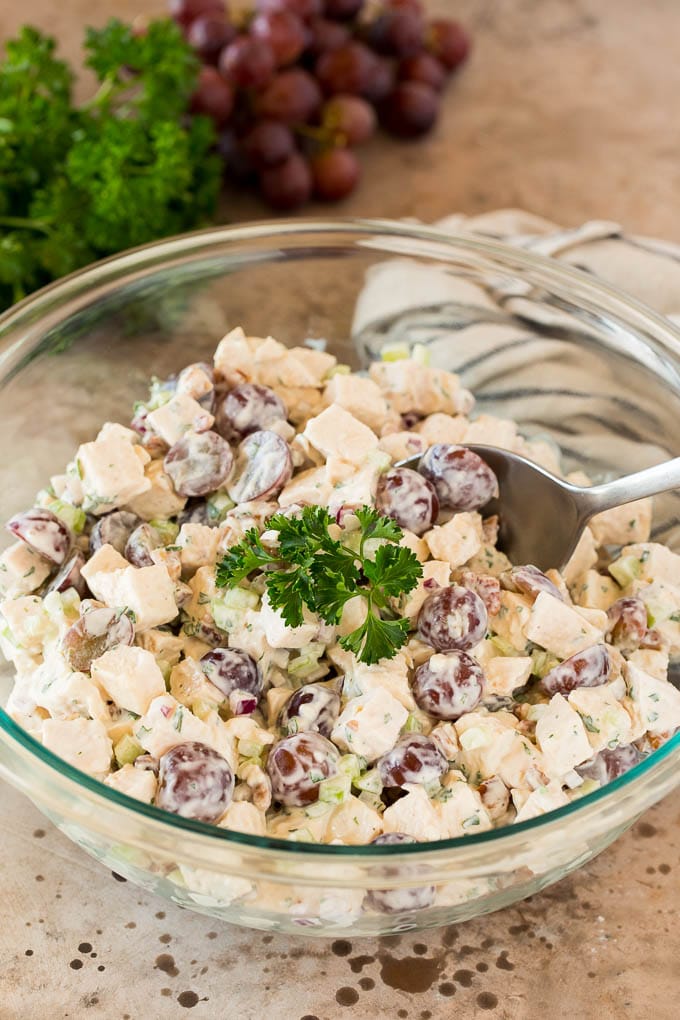 A bowl of chicken salad with grapes, garnished with fresh parsley.