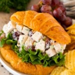 Chicken salad with grapes served on a croissant with chips.