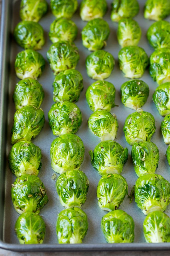 Brussels sprouts lined up face down on a sheet pan.