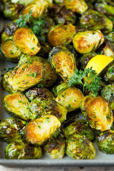 Crispy Brussels sprouts garnished with lemon slices and parsley.