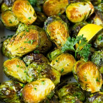 Crispy Brussels sprouts garnished with lemon slices and parsley.