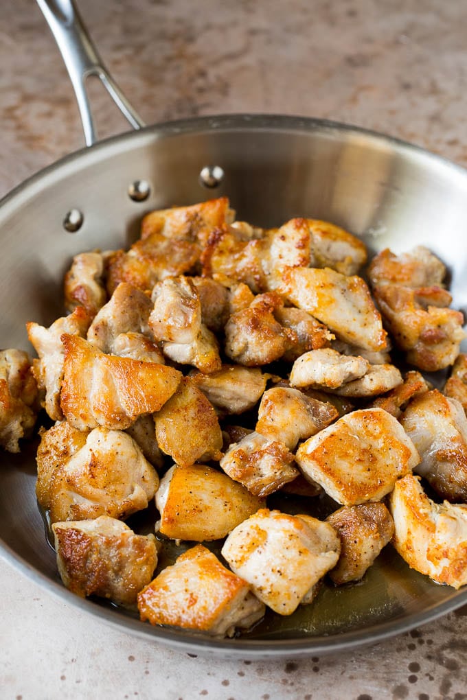 Seared chicken thigh pieces in a pan.