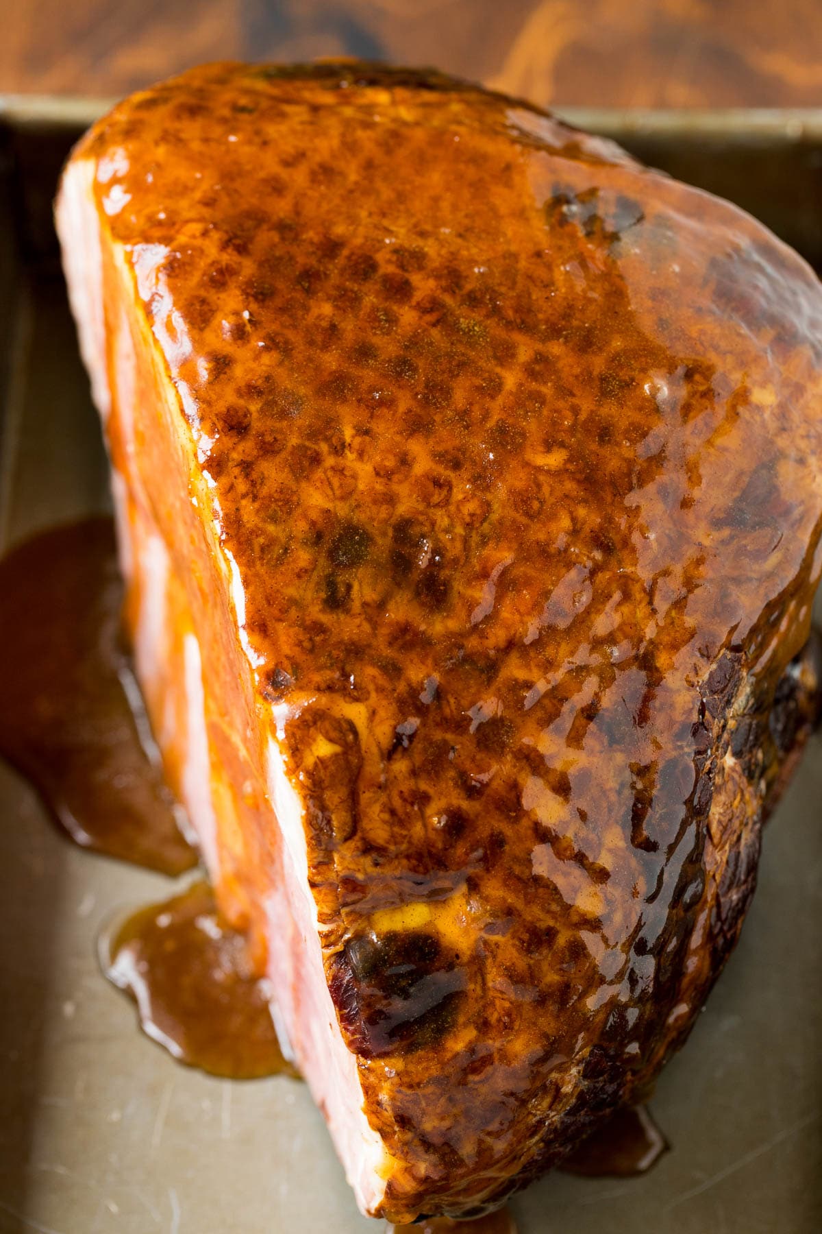 A ham coated in glaze in a baking pan.