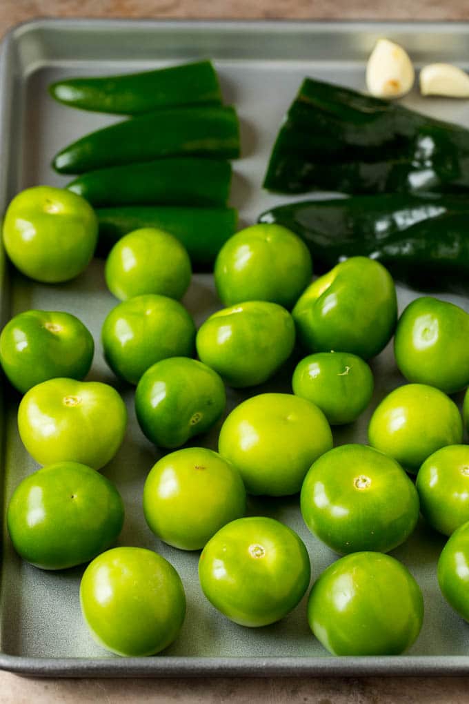 Tomatillos and halved peppers on a sheet pan.