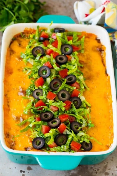 Taco bake topped with melted cheese, lettuce, tomatoes and olives.