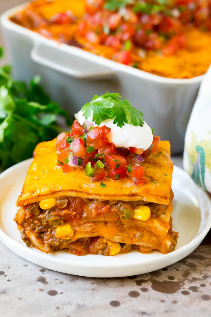 A slice of taco lasagna topped with salsa, sour cream and cilantro.