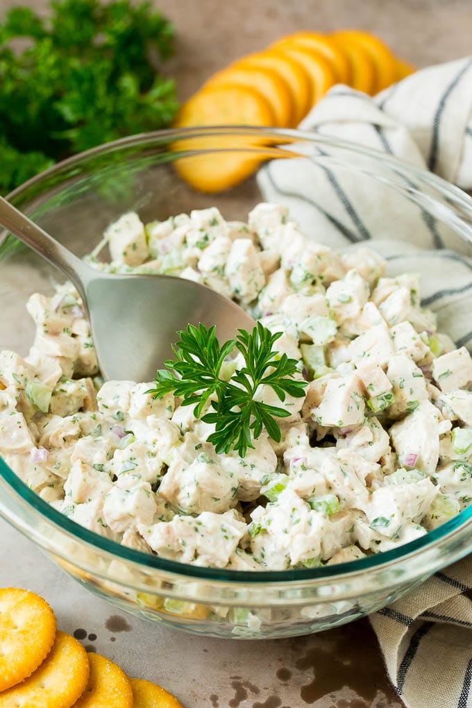 A bowl of creamy turkey salad garnished with parsley and served with crackers.