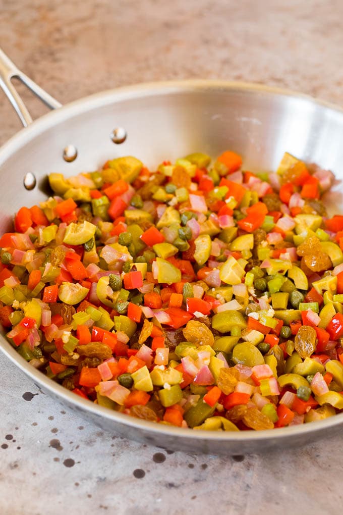 Olives, vegetables and capers in a skillet.