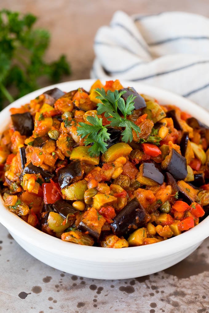 A serving bowl of caponata topped with fresh parsley.