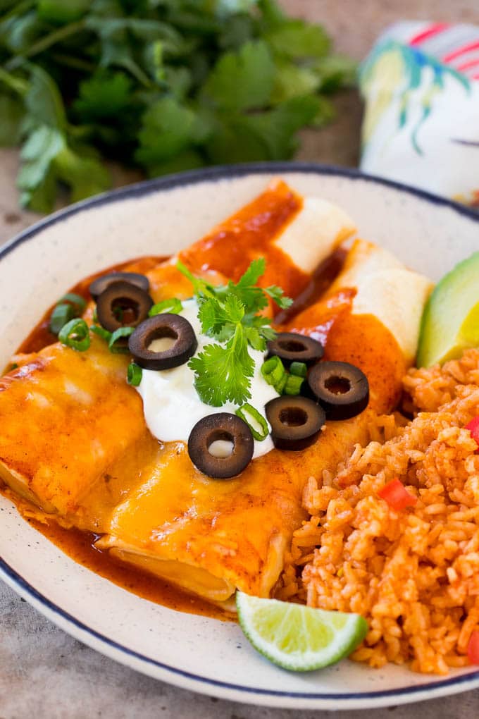 A plate of cheese enchiladas served with Mexican rice.