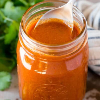 A jar of homemade enchilada sauce with a spoon in it.