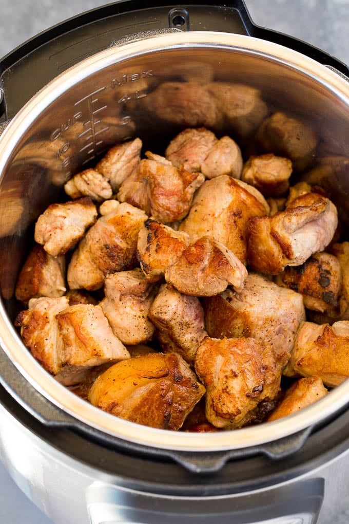 Seared pork pieces in a pressure cooker.