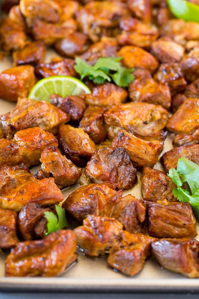 A sheet pan of Instant Pot carnitas garnished with lime and cilantro.