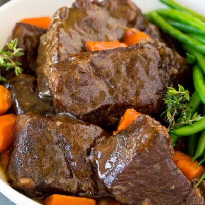 A bowl of Instant Pot short ribs in sauce with carrots and green beans.