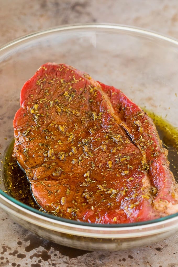 London broil marinade in a bowl with a piece of steak in it.