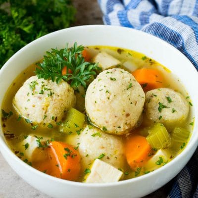 A bowl of matzo ball soup with chicken, garnished with parsley.