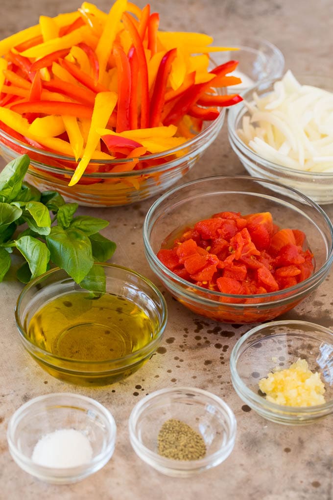 Ingredient bowls of tomatoes, olive oil, seasonings and peppers.