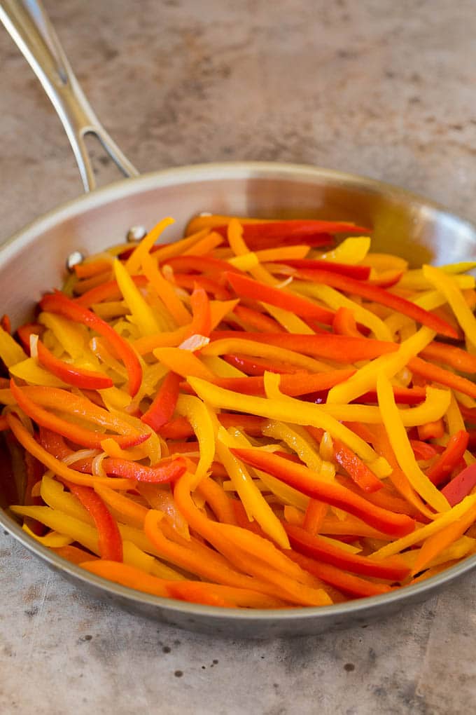 Sliced bell peppers and onions in a pan.