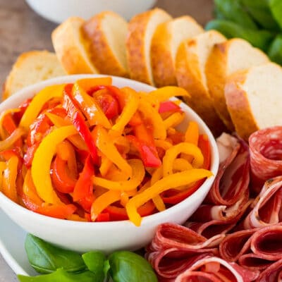 A bowl of peperonata served with cured meats, olives and bread.