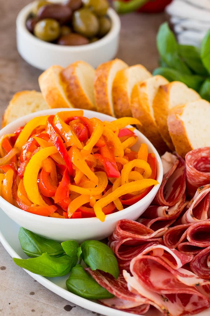 A bowl of peperonata served with cured meats, olives and bread.