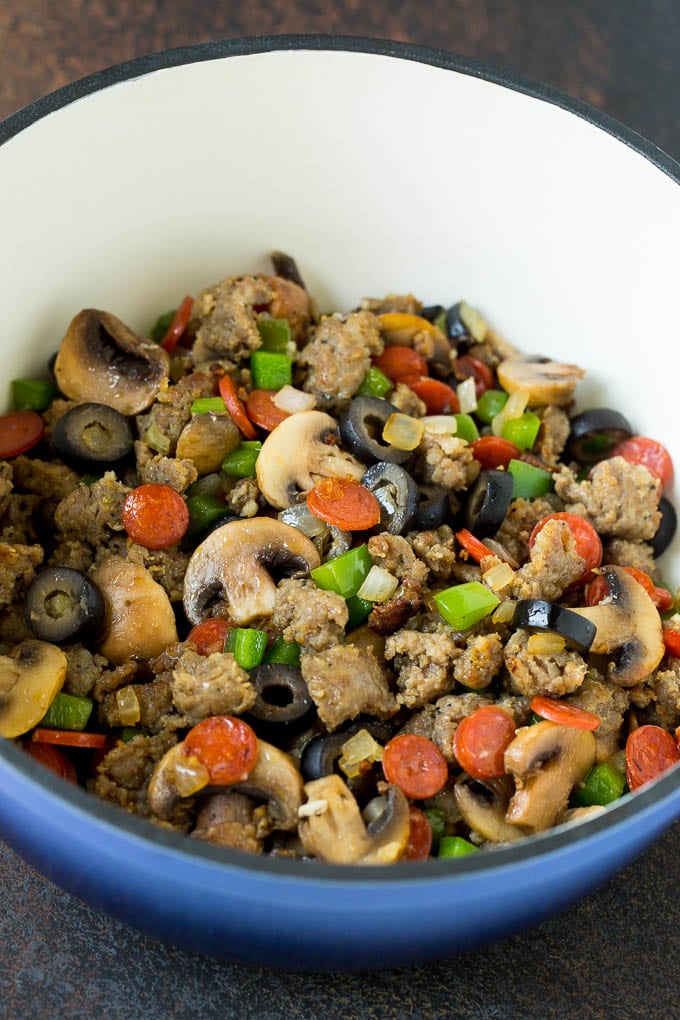 Sausage, mushrooms, olives, pepperoni and peppers in a pot.