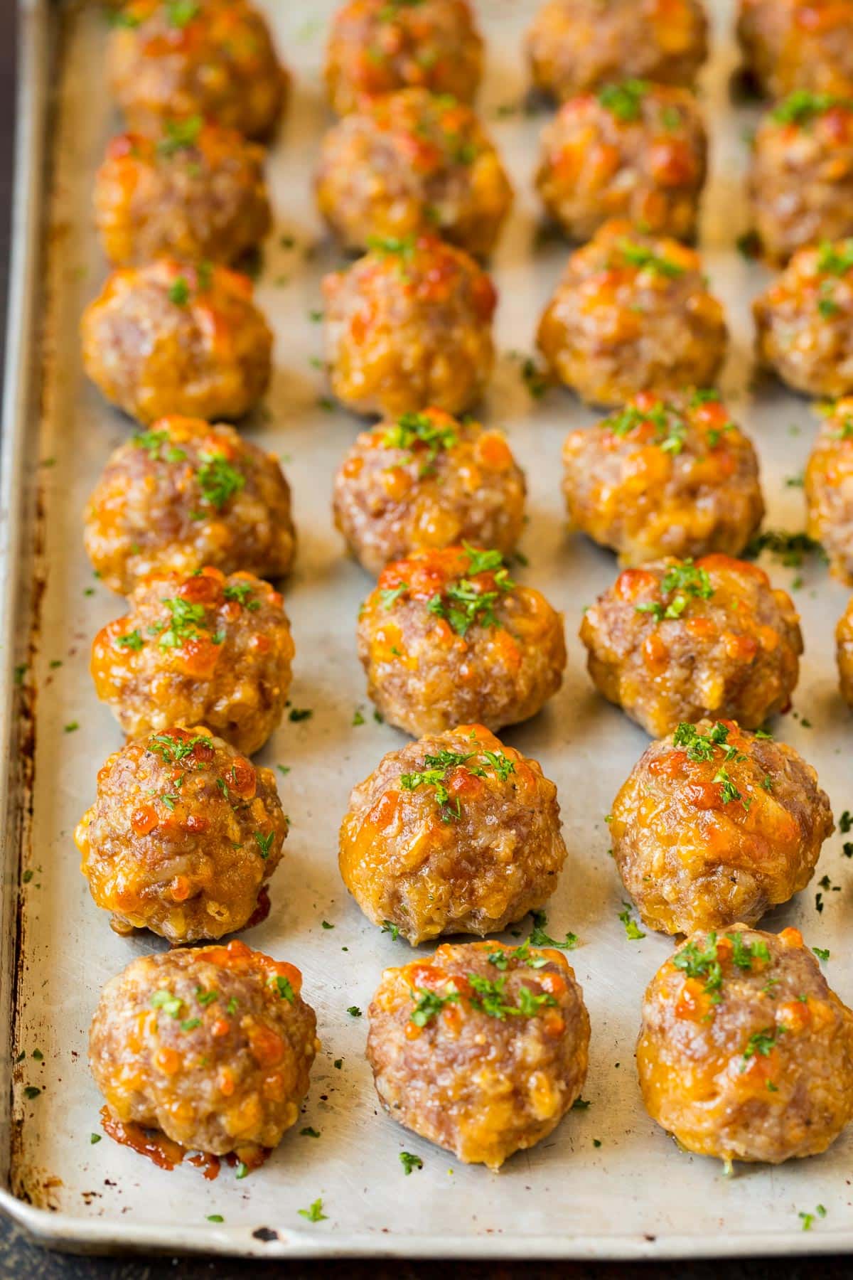 Cooked sausage balls on a pan, topped with parsley.