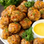 A serving plate of sausage balls served with dip.