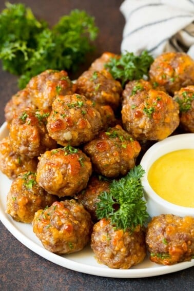 A serving plate of sausage balls served with dip.