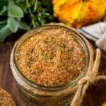 A jar of turkey rub surrounded by squash and herbs.