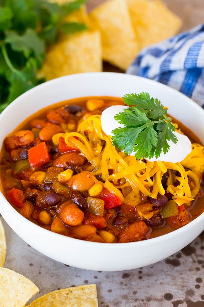 A bowl of vegetarian chili topped with shredded cheese and sour cream.