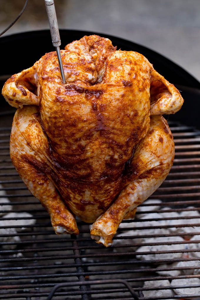 A chicken sitting on top of a charcoal grill.