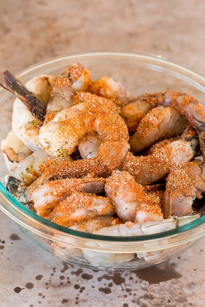 A bowl of raw shrimp coated in seasonings.