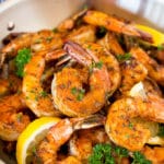 A pan of Cajun shrimp garnished with parsley and lemon.