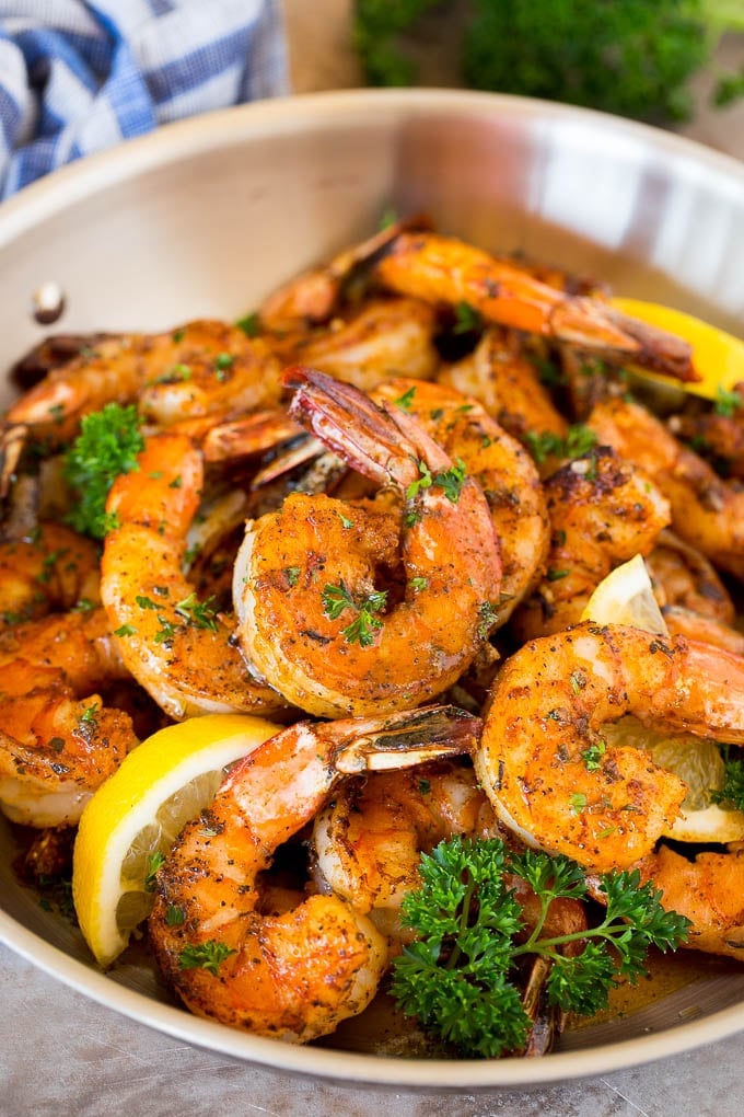 A pan of Cajun shrimp garnished with parsley and lemon.