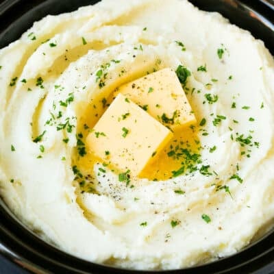 Crock pot mashed potatoes topped with butter and parsley.
