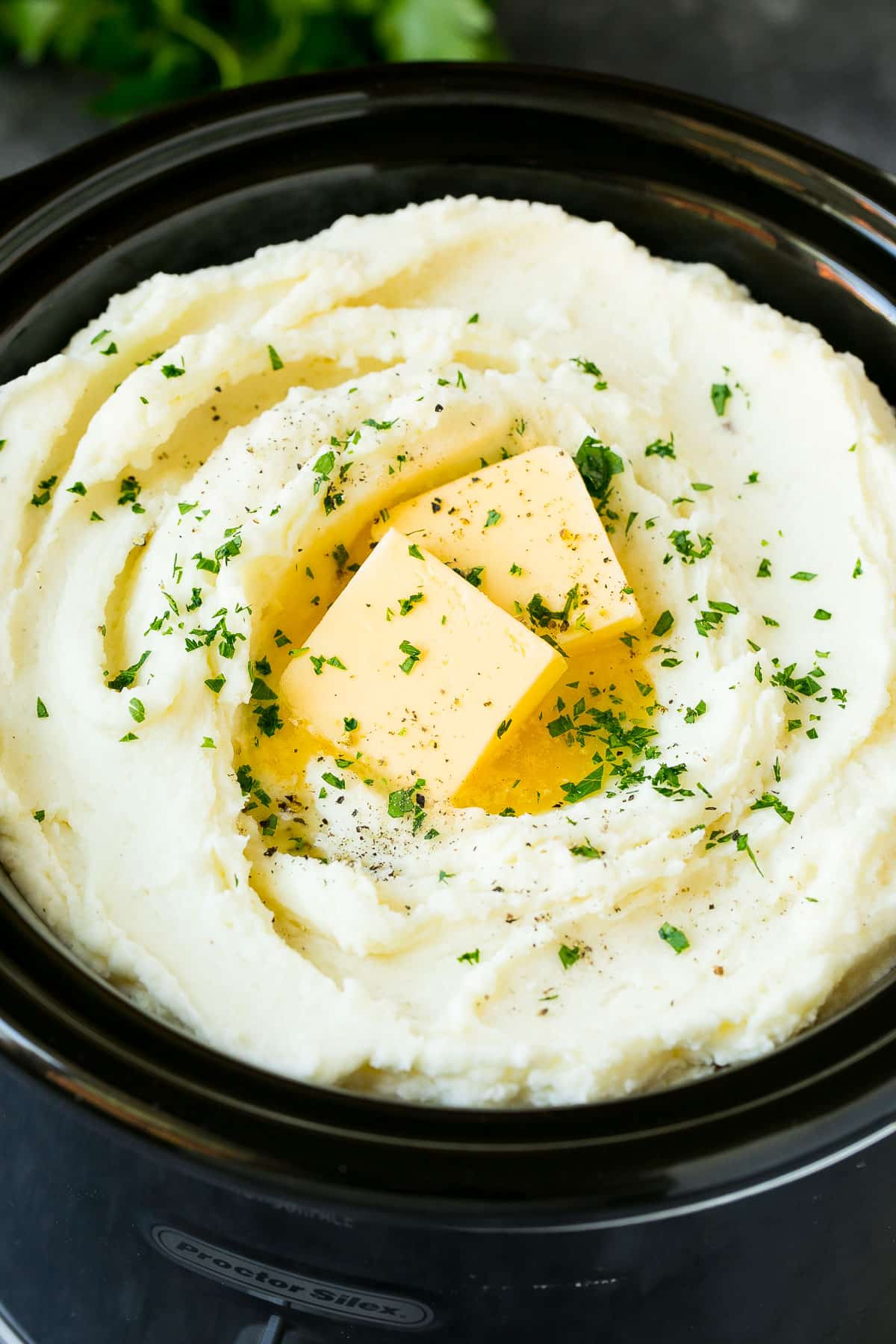 Crock pot mashed potatoes topped with butter and parsley.
