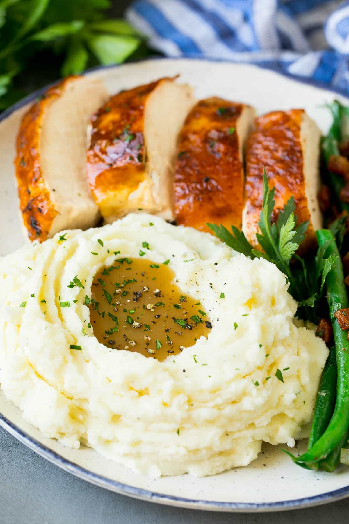 Crock pot mashed potatoes on a plate with turkey, green beans and gravy.