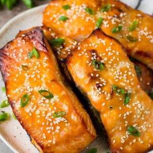 A platter of miso salmon fillets topped with sesame seeds and green onions.