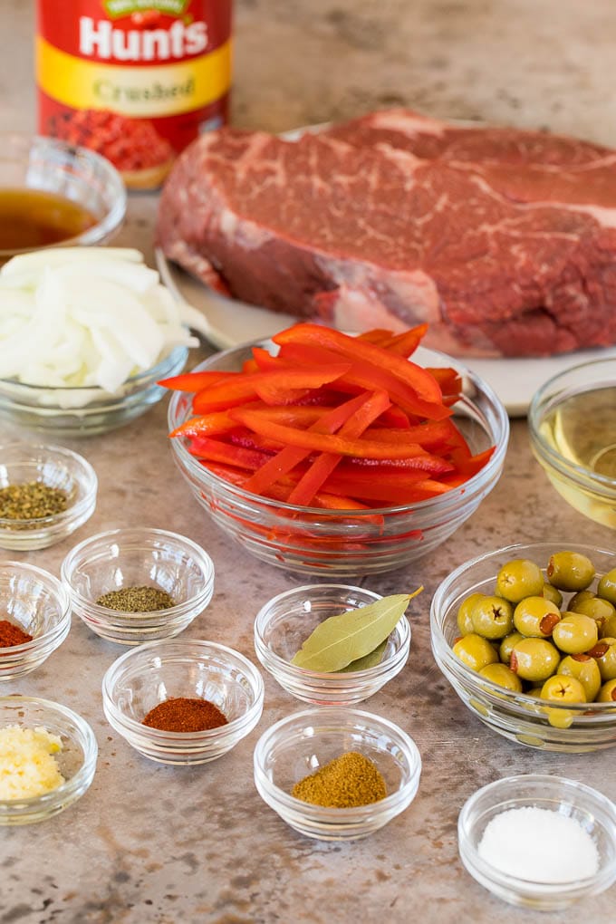 Ingredients in glass bowls including onions, bell pepper, olives and seasonings.