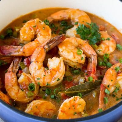 A pot of shrimp etouffee garnished with green onions and parsley.