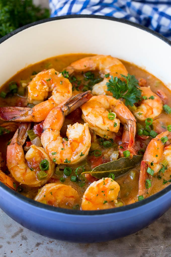 A pot of shrimp etouffee garnished with green onions and parsley.