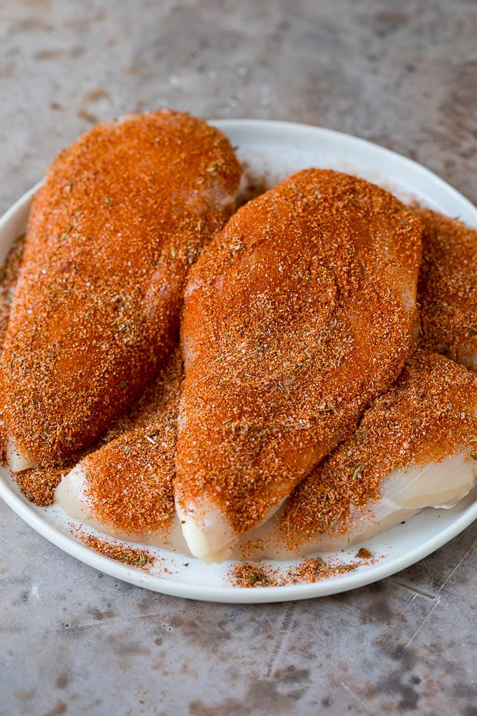 Raw chicken breasts coated in seasonings.