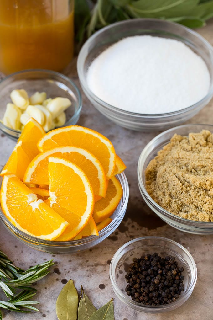Bowls of ingredients including orange slices, brown sugar, garlic, herbs and seasonings.