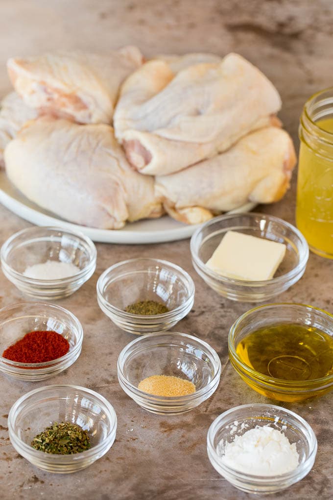 Raw chicken thighs and bowls of seasonings.