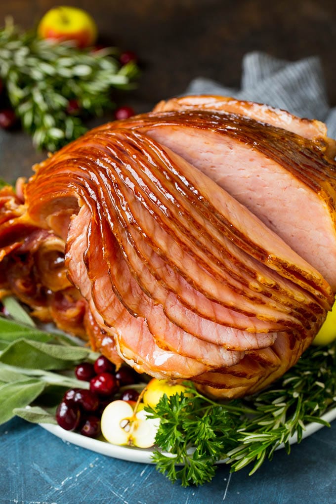 An Instant Pot ham served on a platter with herbs and fruit.